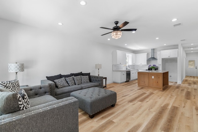 living room featuring ceiling fan, sink, and light hardwood / wood-style floors