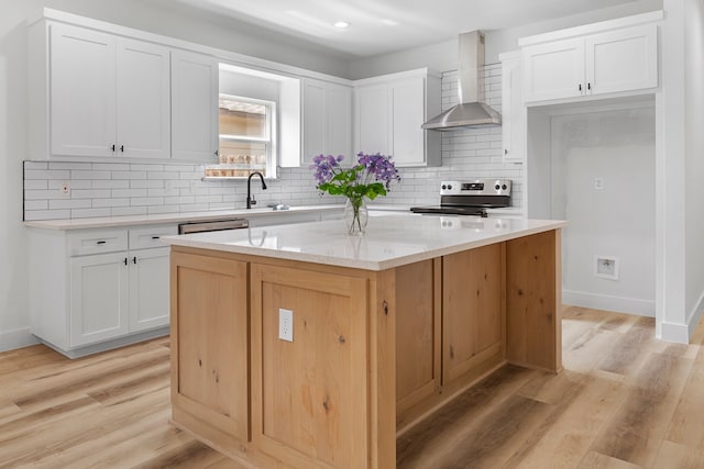 kitchen with tasteful backsplash, wall chimney exhaust hood, stainless steel appliances, white cabinets, and a center island