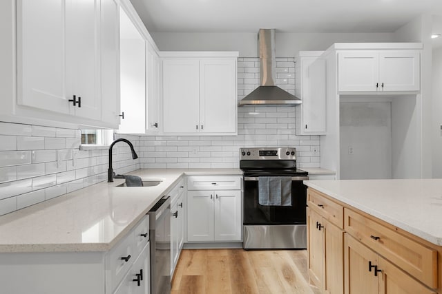 kitchen featuring white cabinetry, wall chimney range hood, sink, and appliances with stainless steel finishes