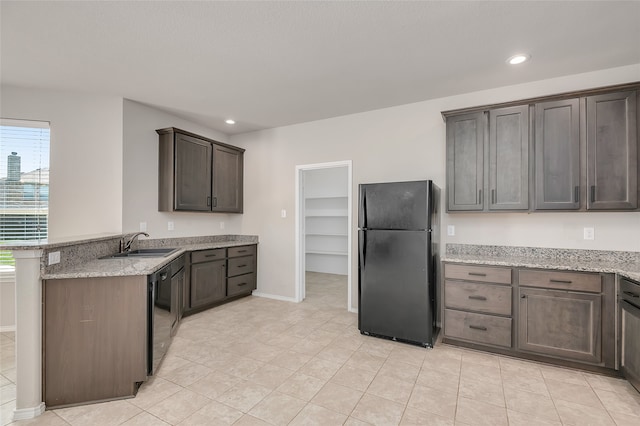 kitchen with black appliances, sink, dark brown cabinetry, light stone countertops, and kitchen peninsula