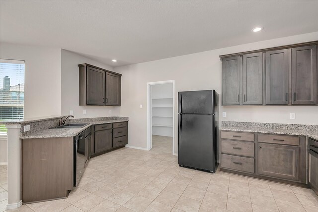 kitchen with dark brown cabinetry, light carpet, ceiling fan, and black appliances