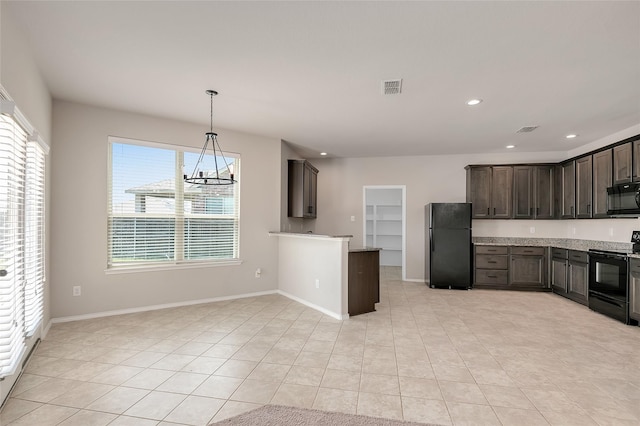 kitchen with light carpet, an inviting chandelier, black appliances, light stone countertops, and dark brown cabinetry