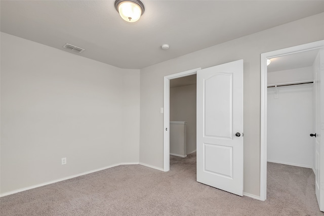 unfurnished bedroom featuring light colored carpet, a spacious closet, and a closet