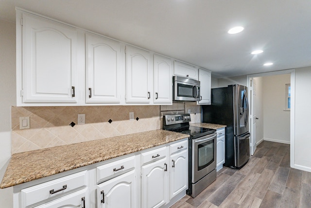 kitchen with decorative backsplash, light hardwood / wood-style floors, white cabinetry, and stainless steel appliances