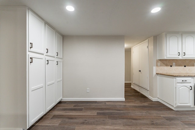 kitchen with decorative backsplash, white cabinetry, stone counters, and dark wood-type flooring