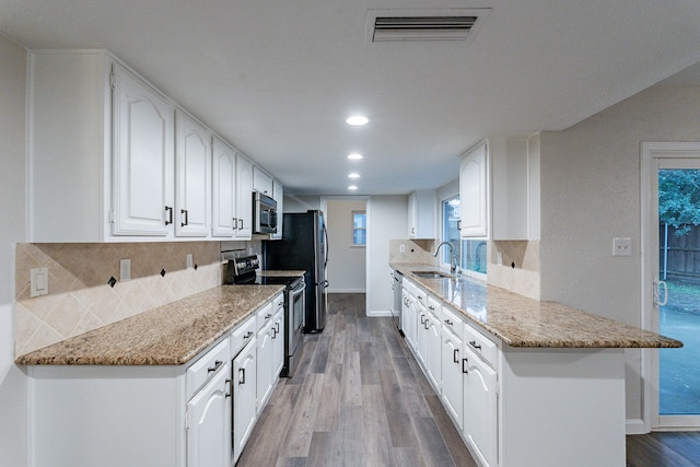 kitchen featuring appliances with stainless steel finishes, light wood-type flooring, white cabinetry, and sink