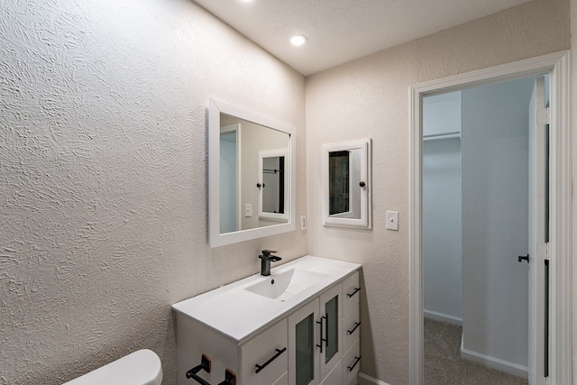 bathroom with vanity, toilet, and a textured ceiling