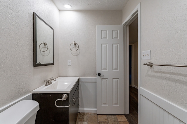 bathroom with vanity, a textured ceiling, and toilet