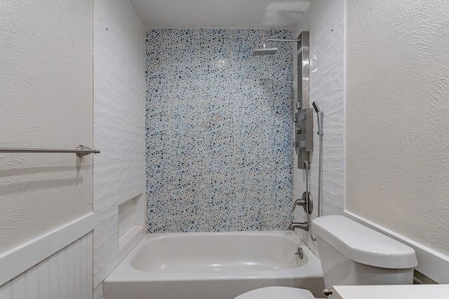 bathroom featuring toilet and tiled shower / bath