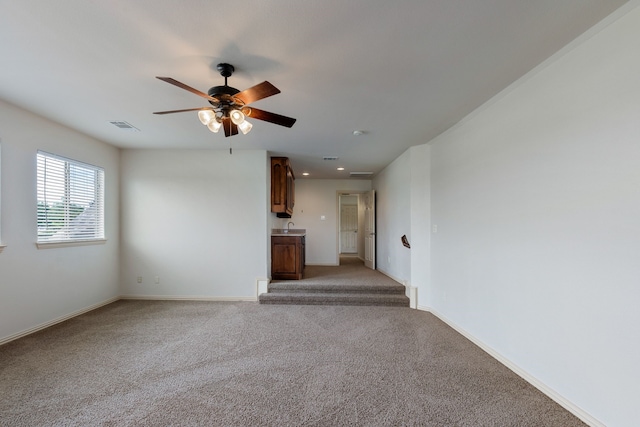 unfurnished living room with light colored carpet, ceiling fan, and sink