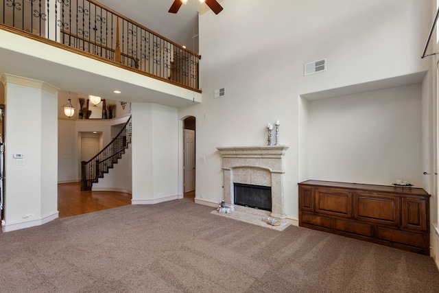 unfurnished living room featuring carpet, a towering ceiling, and ceiling fan