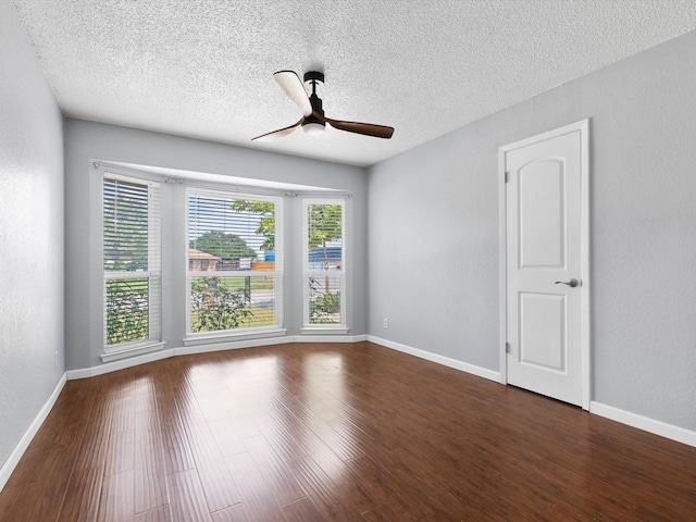 empty room with dark hardwood / wood-style floors, a textured ceiling, and ceiling fan