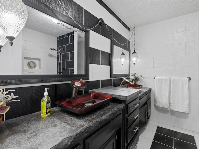 bathroom with a textured ceiling, tile walls, vanity, tile patterned flooring, and decorative backsplash