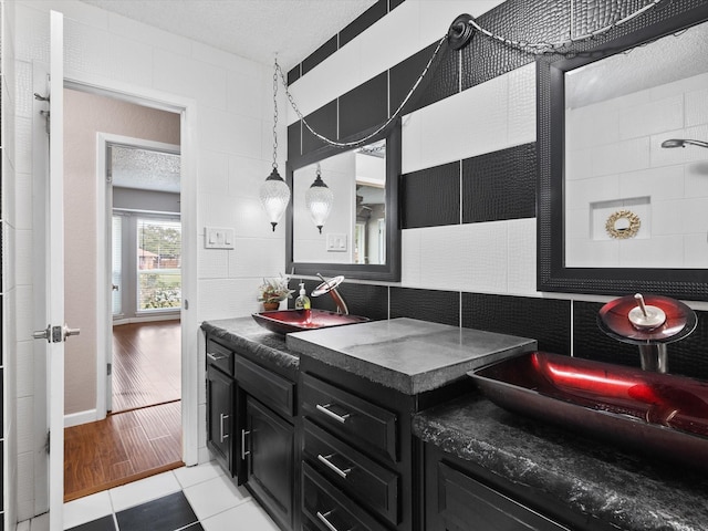 bathroom with tasteful backsplash, vanity, tile walls, and a textured ceiling