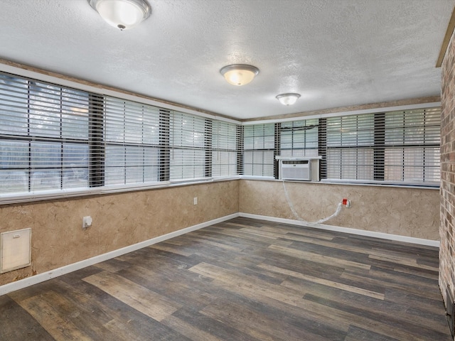 empty room featuring cooling unit, dark hardwood / wood-style flooring, and a textured ceiling