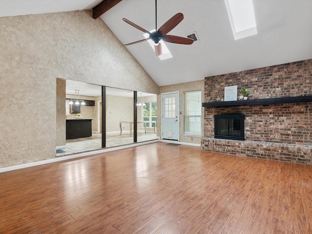 unfurnished living room with a brick fireplace, a skylight, hardwood / wood-style floors, and ceiling fan