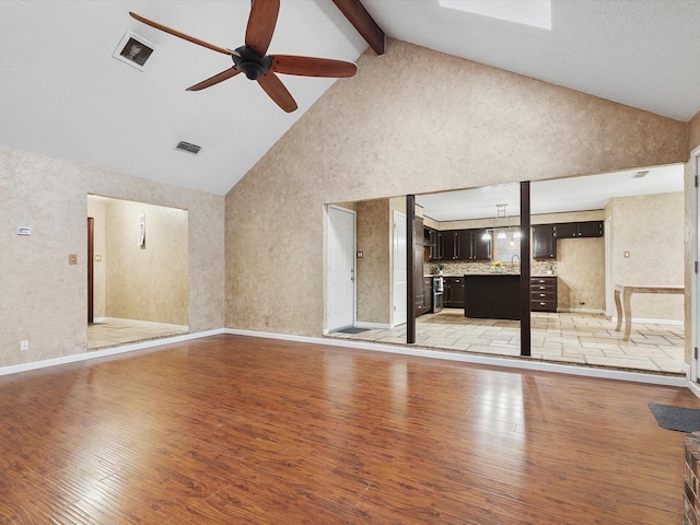 unfurnished living room featuring beam ceiling, light hardwood / wood-style flooring, high vaulted ceiling, and ceiling fan