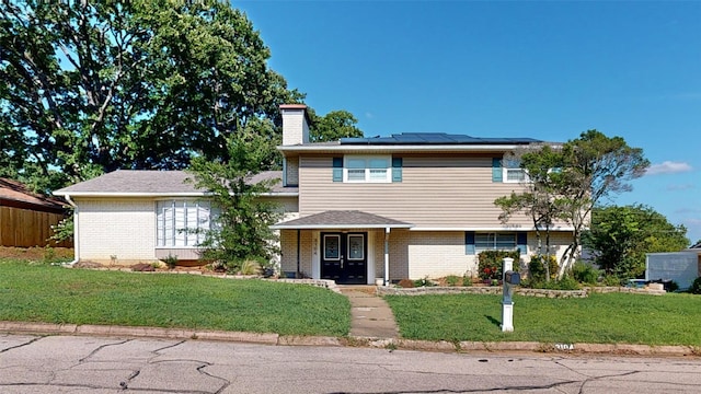 view of front of home featuring solar panels, covered porch, and a front lawn