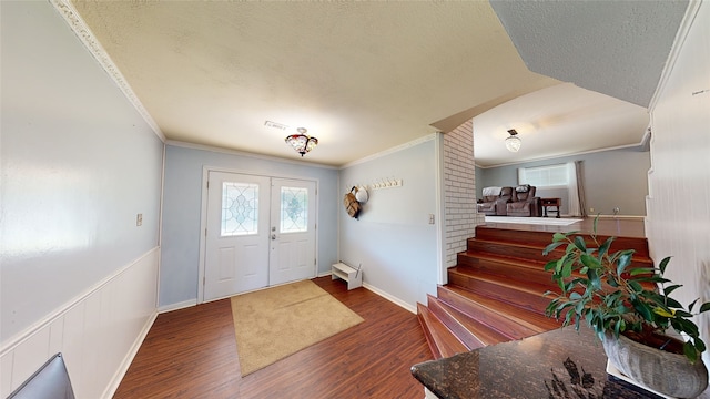 foyer entrance with crown molding, dark wood-type flooring, and a textured ceiling