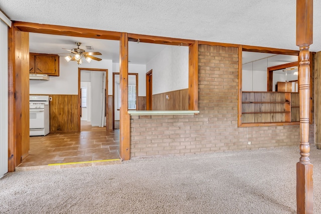 unfurnished living room featuring a wealth of natural light, carpet, beamed ceiling, and wooden walls