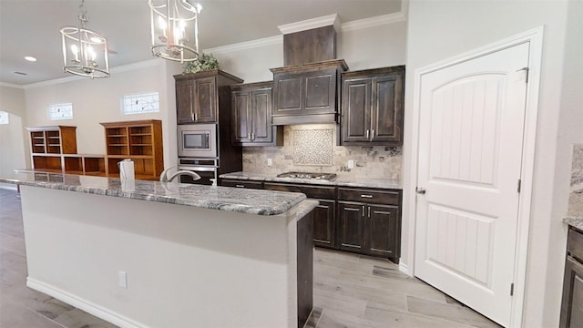 kitchen featuring decorative light fixtures, light hardwood / wood-style flooring, stainless steel appliances, crown molding, and a kitchen island with sink