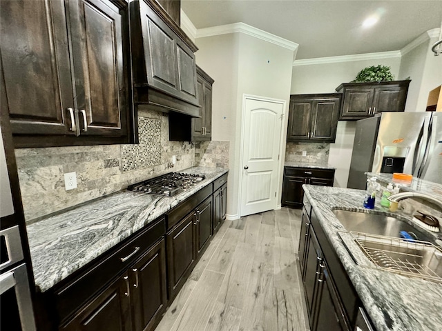 kitchen with stainless steel appliances, ornamental molding, light hardwood / wood-style flooring, and tasteful backsplash