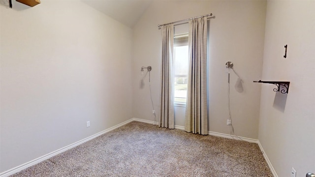 carpeted spare room featuring vaulted ceiling and baseboards