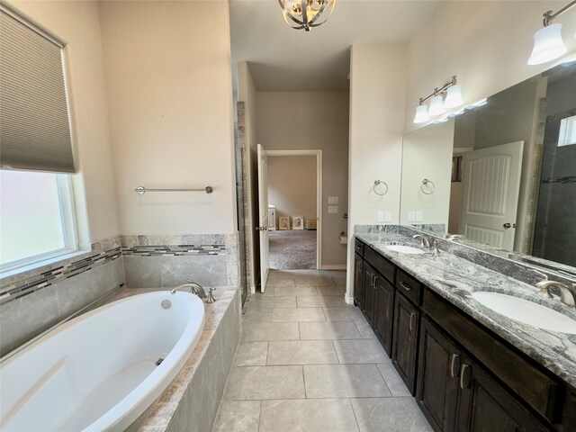 bathroom with tile floors, tiled bath, oversized vanity, and dual sinks