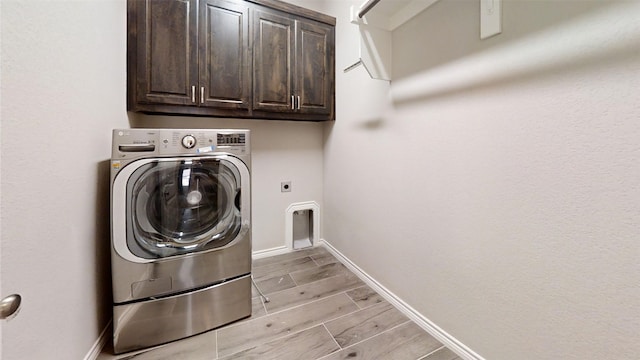 laundry room featuring baseboards, wood tiled floor, washer / clothes dryer, and cabinet space