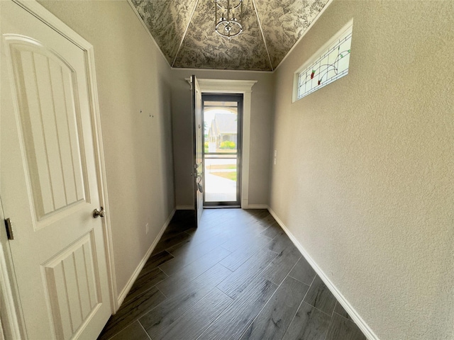 doorway with a textured wall, baseboards, and dark wood-style flooring