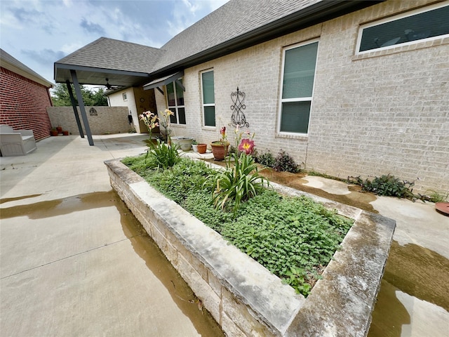 exterior space featuring fence, brick siding, a shingled roof, ceiling fan, and a patio