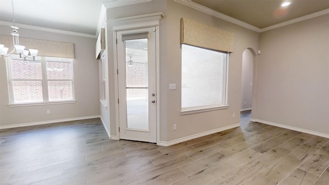 entryway featuring baseboards, wood finished floors, a notable chandelier, and ornamental molding