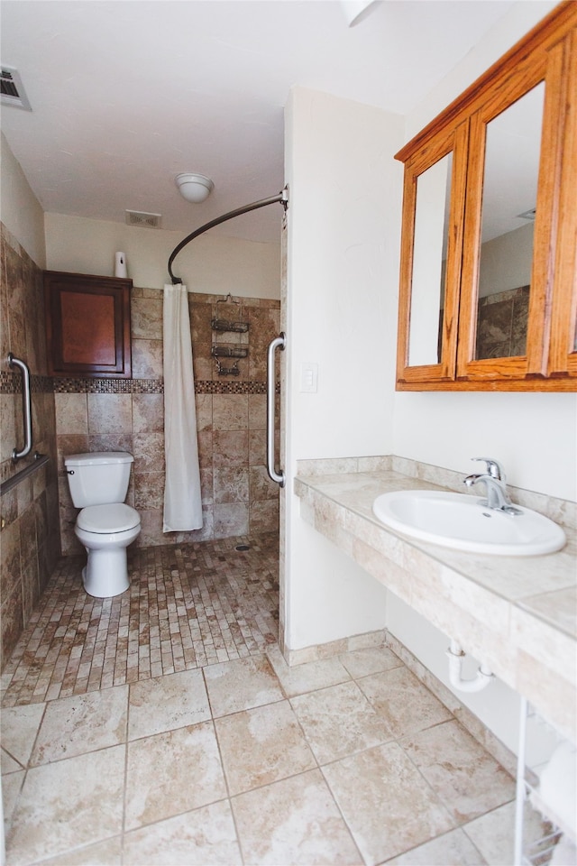 bathroom with sink, a shower with curtain, tile patterned flooring, toilet, and tile walls