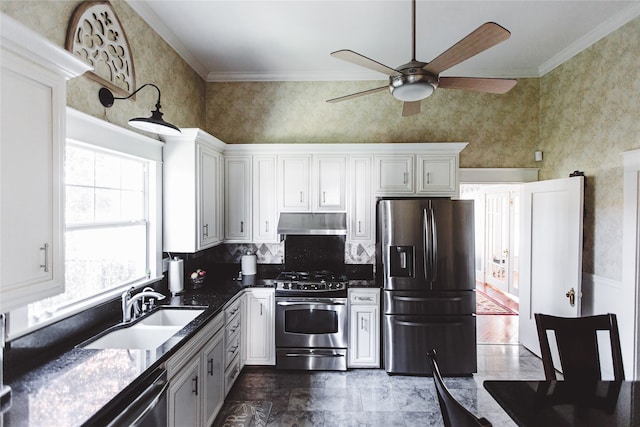 kitchen with a towering ceiling, ornamental molding, stainless steel appliances, sink, and white cabinets