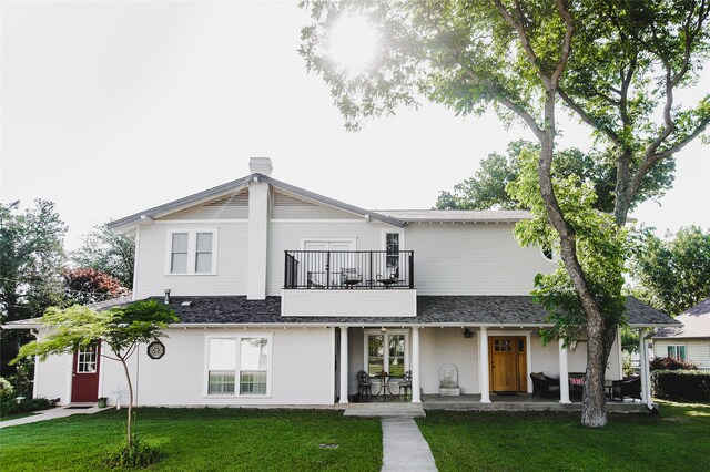 view of front of property featuring a balcony and a front lawn