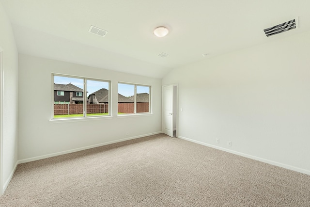 carpeted empty room featuring vaulted ceiling