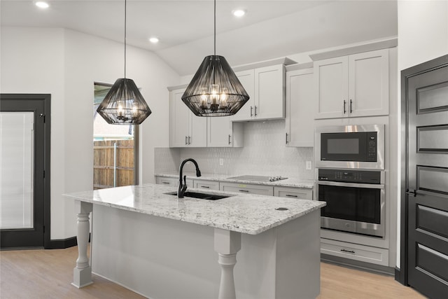 kitchen featuring built in microwave, sink, stainless steel oven, an island with sink, and white cabinets