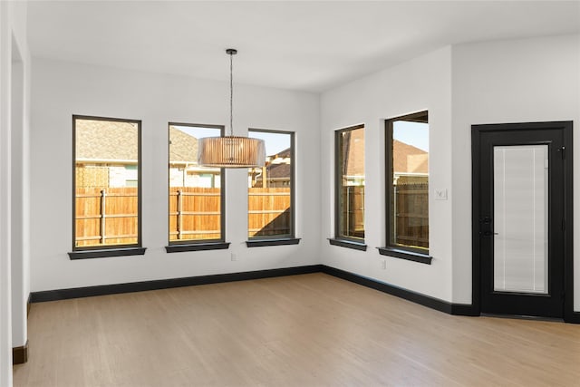 spare room featuring a notable chandelier and light wood-type flooring