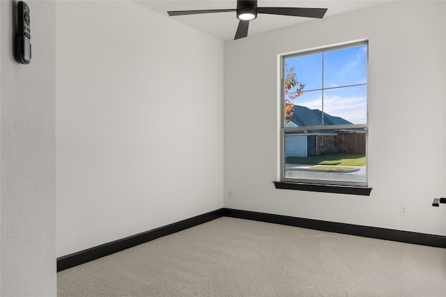 spare room with a mountain view, carpet, and ceiling fan