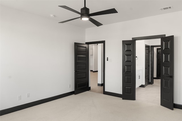 unfurnished bedroom featuring ceiling fan, light colored carpet, and connected bathroom