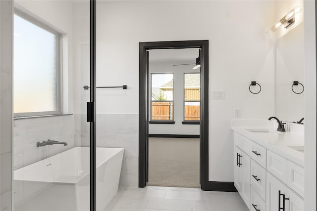 bathroom featuring tile patterned flooring, vanity, tile walls, and a tub