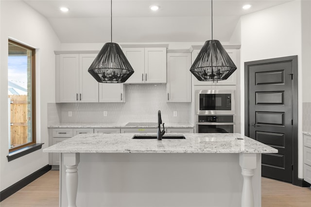 kitchen featuring stainless steel appliances, white cabinetry, and an island with sink