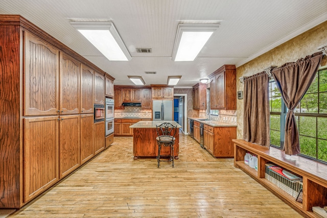 kitchen featuring a center island, light hardwood / wood-style floors, a kitchen breakfast bar, and appliances with stainless steel finishes