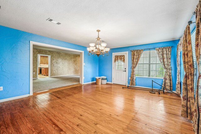 interior space featuring a textured ceiling, hardwood / wood-style floors, and a chandelier