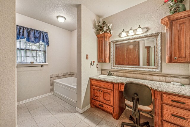 bathroom featuring a textured ceiling, tile patterned floors, vanity, and a bathtub