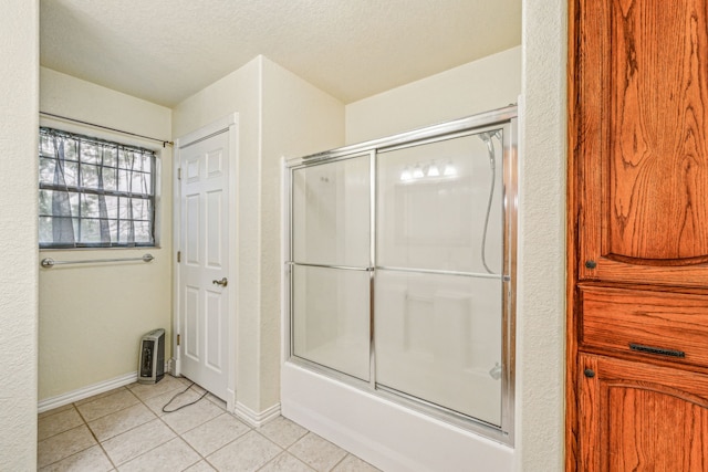 bathroom with a textured ceiling, tile patterned floors, and combined bath / shower with glass door