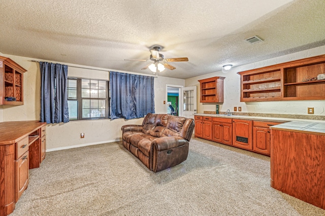 carpeted living room featuring sink, a textured ceiling, and ceiling fan