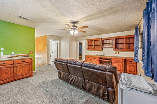 carpeted living room featuring a textured ceiling and ceiling fan