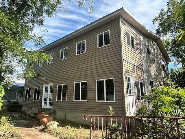 view of home's exterior featuring entry steps, french doors, metal roof, and fence