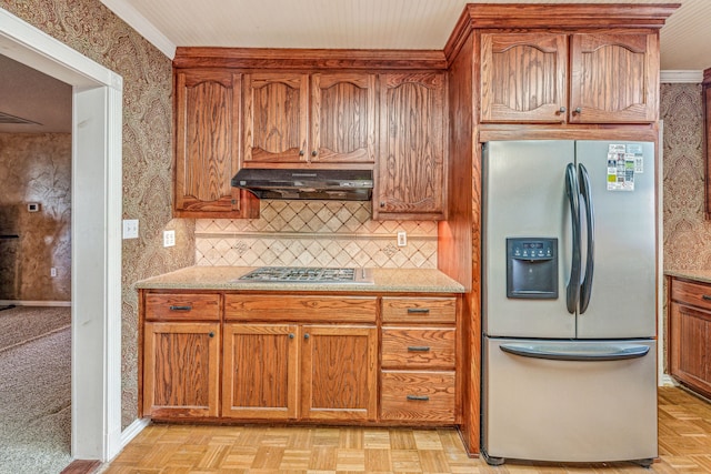 kitchen with tasteful backsplash, appliances with stainless steel finishes, brown cabinets, and range hood